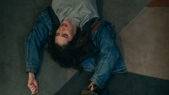 Lizzy Caplan is dragged across concrete in this image from the movie 'Drag.'